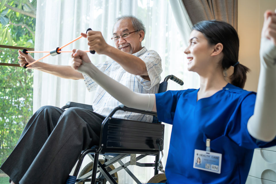 Nurse helping a senior man in wheelchair with exercises.