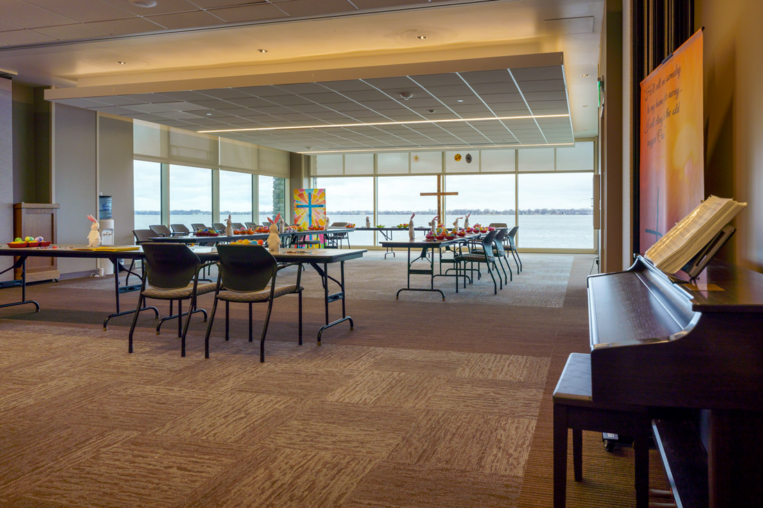 Bayside View Multipurpose room with several tables and chairs and a beautiful look of Storm Lake. The room is decorated with crosses and Easter decor.