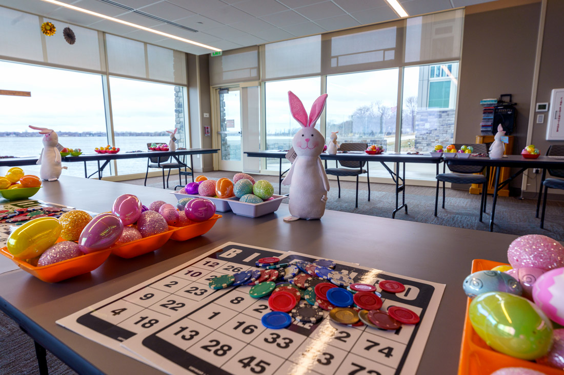 Bayside View Multipurpose room with Easter decorations, bingo cards, and floor-to-ceiling windows with a view of Storm Lake