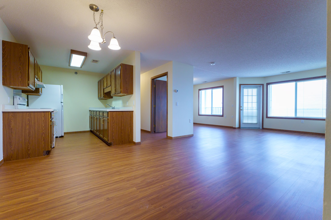 Lake Pointe Villa resident room showing galley kitchen and spacious living area with lots of natural light.